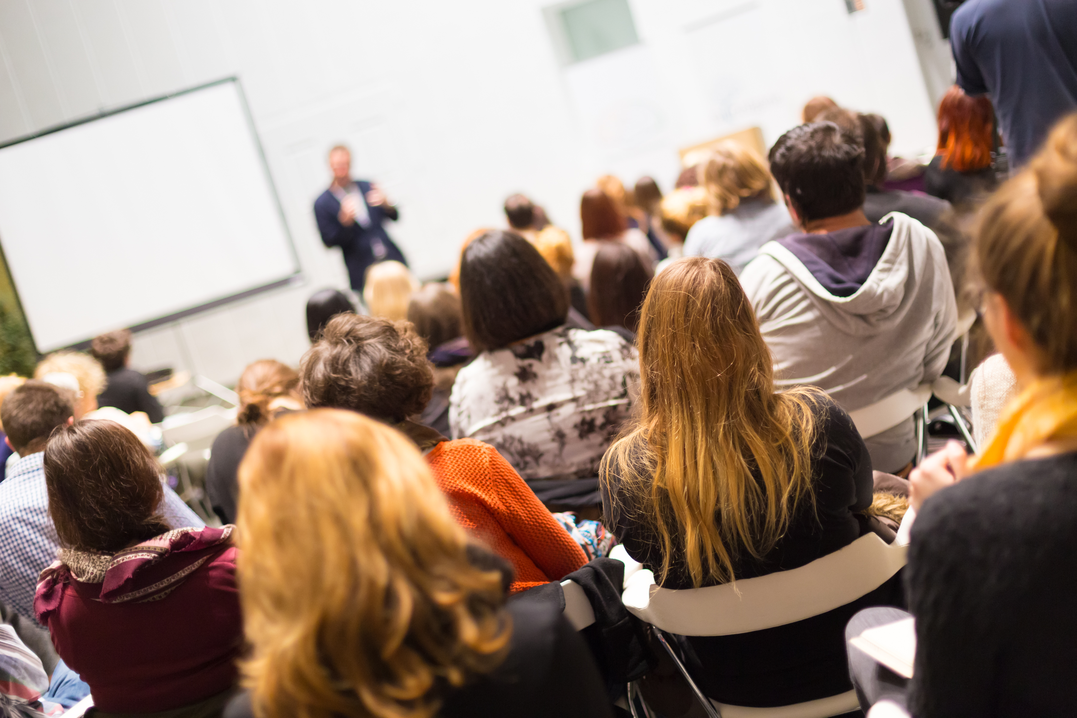 Students in a lecture facing the whiteboard and speaker